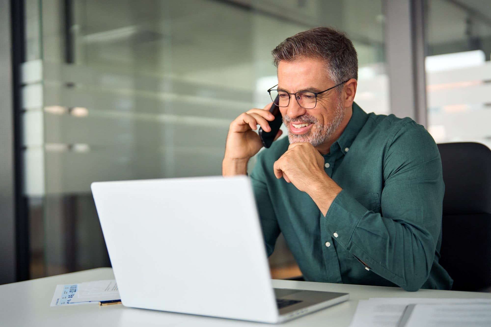 Smiling businessman talking on his phone at his desk