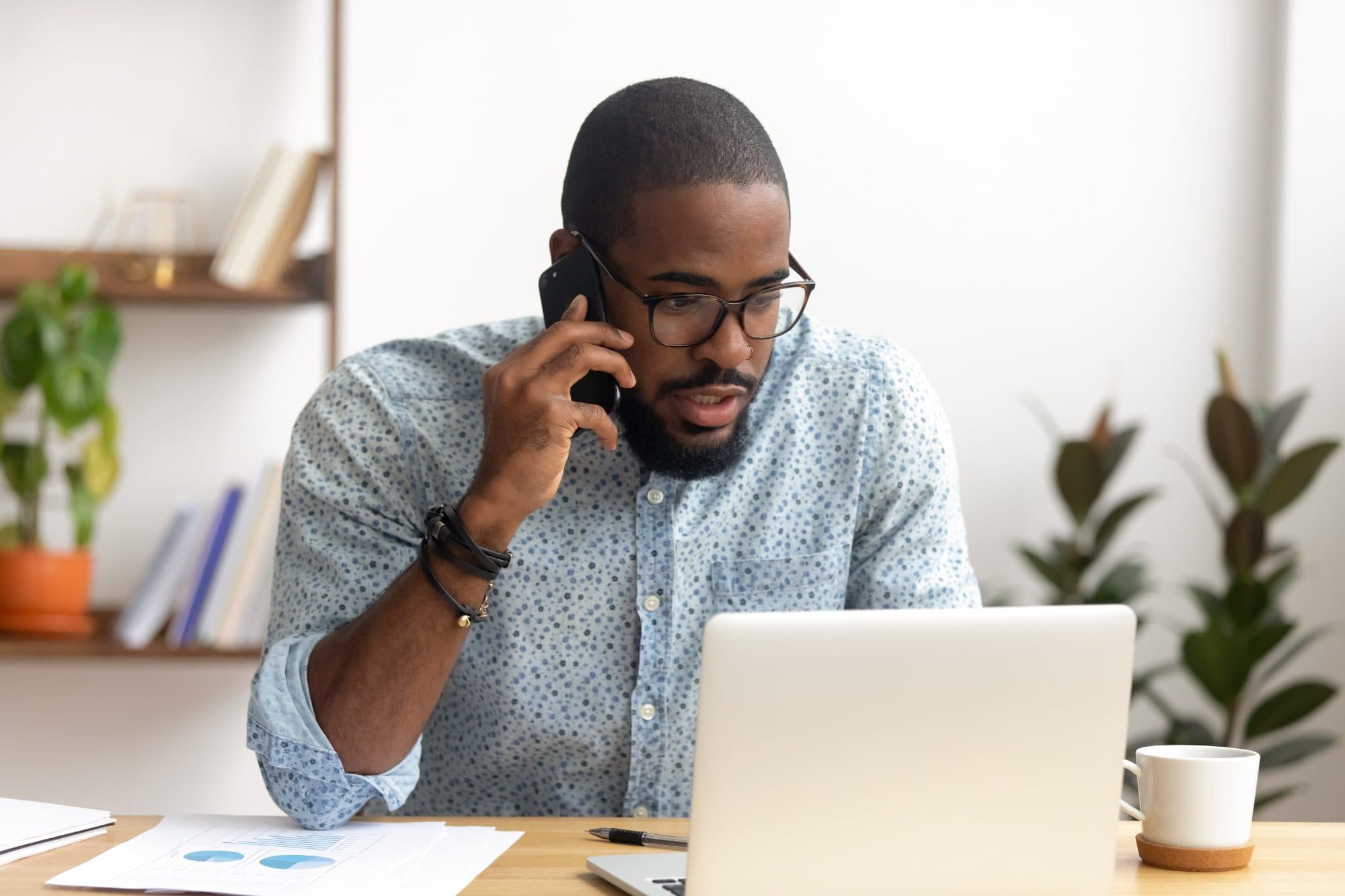 Businessman on a mobile phone call while working on his laptop