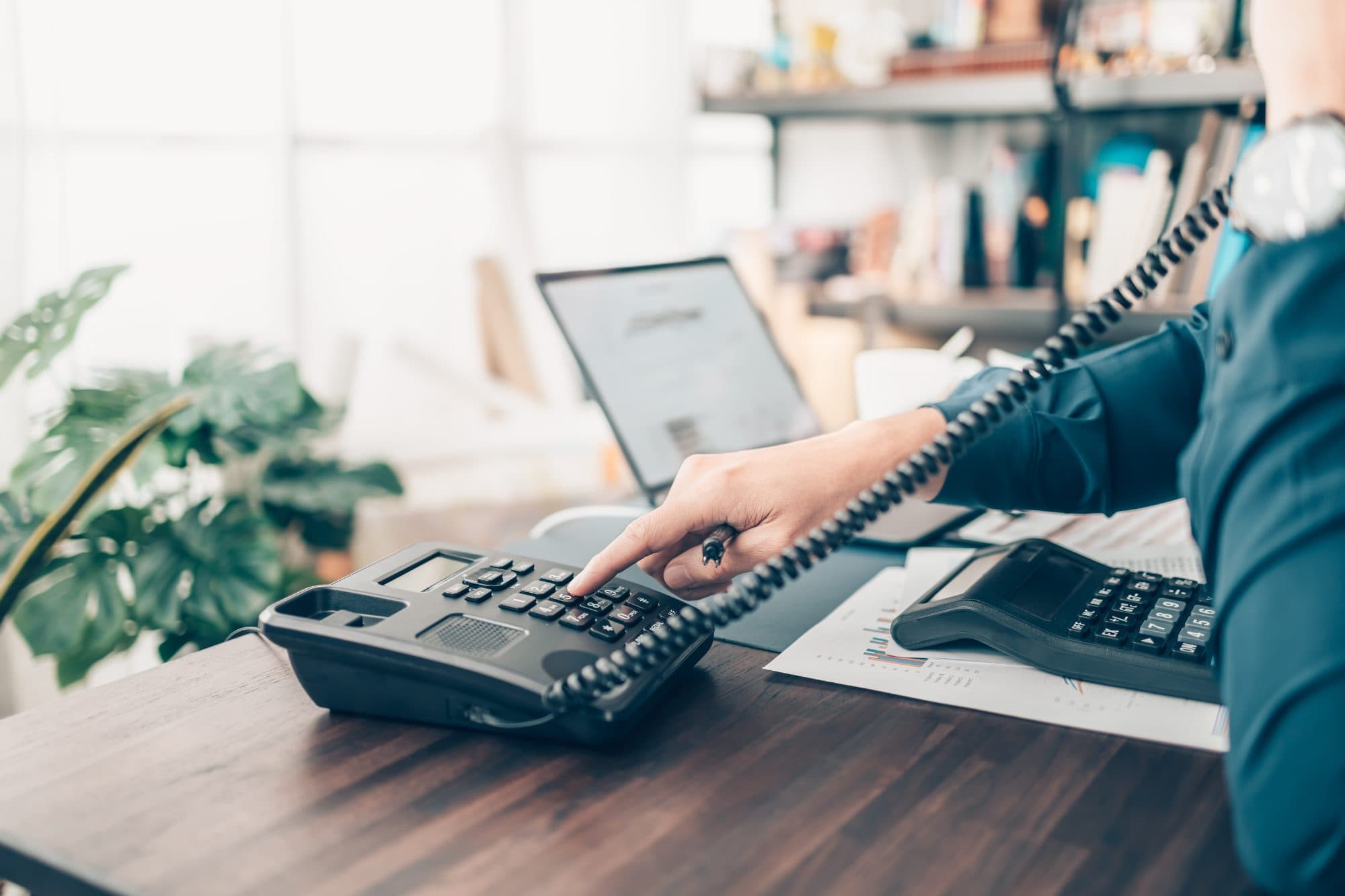 Person dialing an extension on an office desk phone